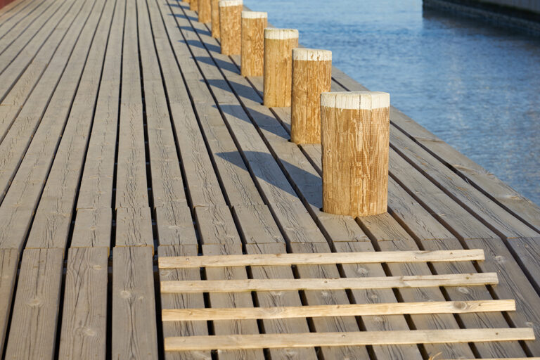 Wooden mooring bollards with shadows on the mole